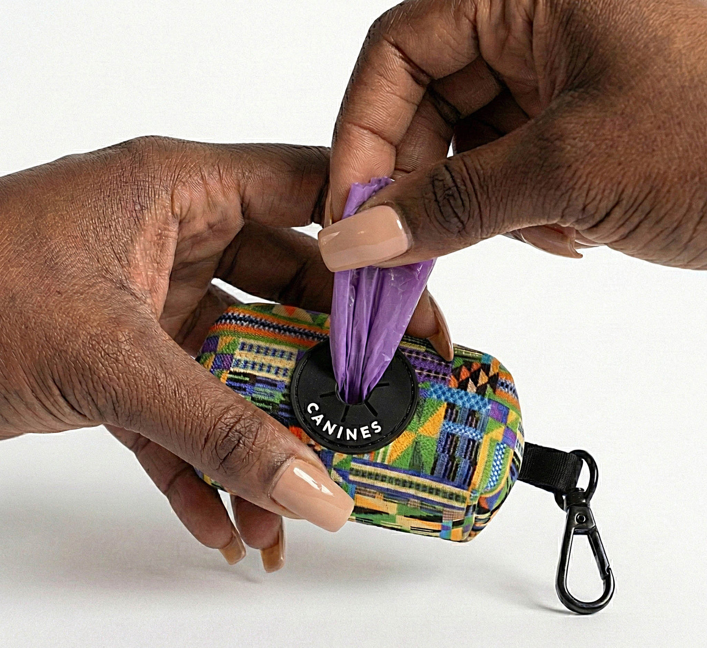 Kente Canines Jungle Green dog waste poop bag dispenser with a purple bag being pulled out, held by two hands.